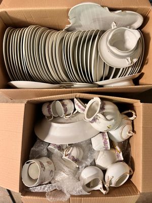 de nombreuses assiettes et tasses dans une boîte posée par terre