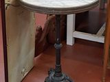 une petite table au plateau en marbre posée sur un sol rouge