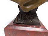 bronze statue of a man with a hat on top of a red marble base