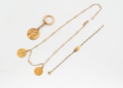 trois colliers en or et une pièce de monnaie sur fond blanc