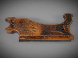 an old wooden comb with a design on it on a gray surface