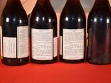four bottles of wine are lined up on a red table