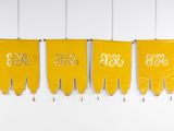 three yellow pennants hanging on a wall with numbers on them