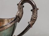 a silver cup with a handle on a table