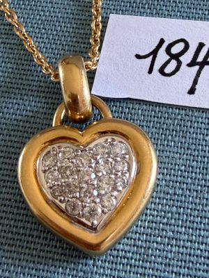 une photo d'un pendentif en or en forme de cœur, orné de diamants, suspendu à une chaîne