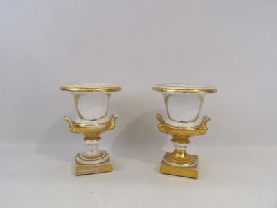 pair of gold and white vases on pedestals against a white background