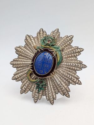 a close up of a brooch with a blue stone in the center