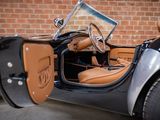 a black and tan car parked in front of a brick wall