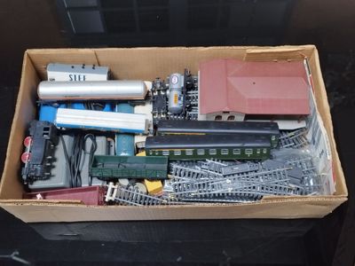une boîte remplie de rails de train miniature et d'autres jouets