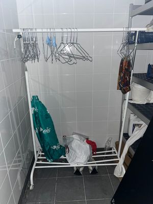 un porte-vêtements blanc sur lequel sont suspendus des vêtements, dans une salle de bains