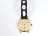 an image of a gold watch with black leather strap