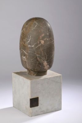 sculpture of a rock on top of a block on a white surface