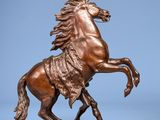 bronze statue of a horse on a rock on a blue background