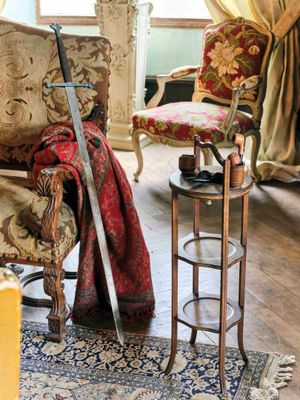 un salon avec un canapé, un fauteuil, une table et une épée