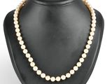 un collier de perles blanches sur un mannequin avec un fermoir en or