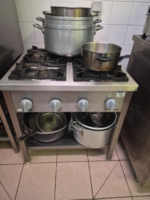 des casseroles et des poêles sont posées sur une cuisinière en acier inoxydable dans une cuisine professionnelle