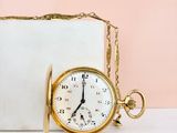 a gold pocket watch sitting next to a white box