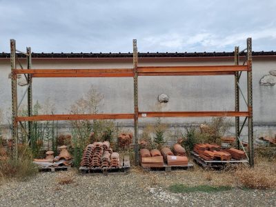 de nombreuses piles de briques posées sur des palettes devant un bâtiment