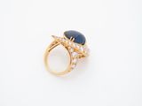 a close up of a gold ring with a blue stone and diamonds