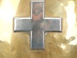 a silver cross on a gold plate with a picture of jesus on it
