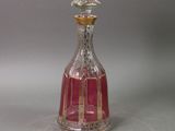a pink glass bottle with a gold top on a table
