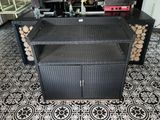 une photo d'un banc en osier noir sur lequel sont empilées des bûches