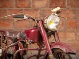a old red motorcycle parked in front of a brick wall