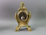 a gold clock with a black face on a gray background