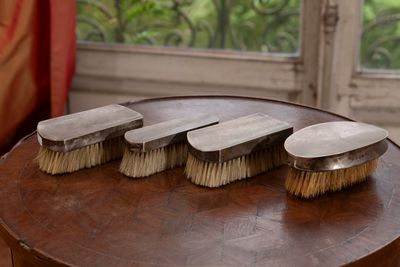 quatre pinceaux posés sur une table en bois devant une fenêtre