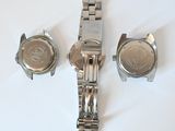three watches are sitting on a white surface with a white background