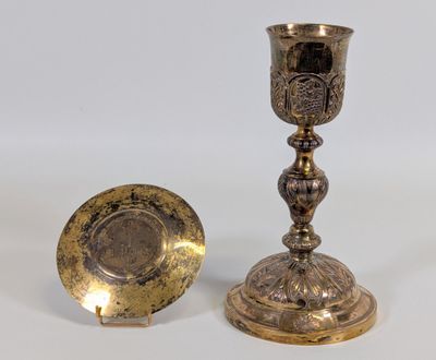 une paire de bougeoirs anciens en laiton et une assiette sur fond blanc