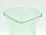 a green glass vase sitting on a white surface