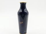 un vase noir orné de motifs dorés sur un fond blanc