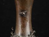 un vase en argent orné d'un oiseau sur fond noir