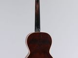 a small wooden guitar hanging from a white wall