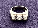 a close up of a ring with three diamonds on a purple surface