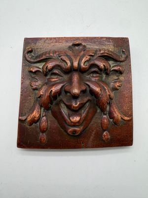 a plaque with a face on it on a wall