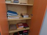 une armoire ouverte sur laquelle sont posés des livres, dans une pièce