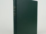 un livre vert orné de lettres dorées, posé sur une surface blanche