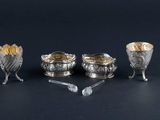 three silver plated dishes and spoons on a black surface