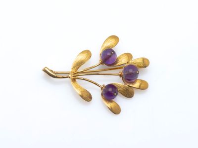 un gros plan d'une broche en or ornée de pierres violettes