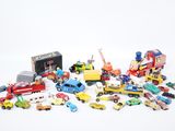un tas de petites voitures et de camions jouets posés sur une surface blanche