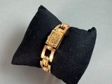 a gold watch sitting on top of a black pillow