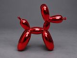 a red balloon dog sculpture on a gray surface