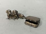 une figurine de chien en argent posée à côté d'une boîte sur une table
