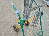 a green cart with a metal handle on the ground
