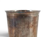 a metal cup that is sitting on a white surface