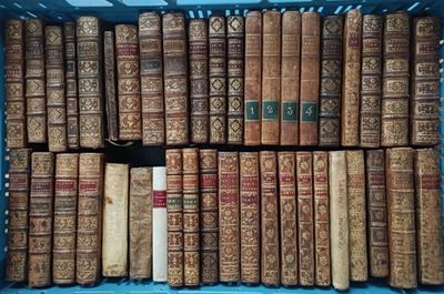 many old books in a blue crate on the floor