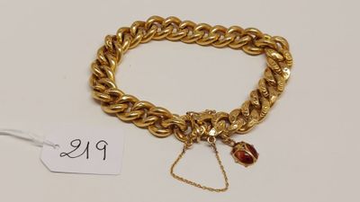 un bracelet en chaîne d'or orné d'une breloque en forme de perle rouge