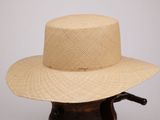 une photo d'un chapeau de paille posé sur un support en bois